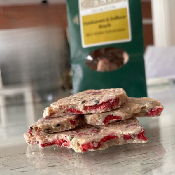 Stapel Stücke Bio Hanfschokolade: weiße Schokolade mit gerösteten geschälten Hanfsamen und getrockneten Erdbeeren, Österreich.