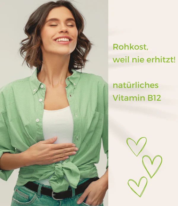 Frau im grünen Hemd legt die Hand auf den Bauch; daneben Text „Rohkost, weil nie erhitzt!“ und „natürliches Vitamin B12“ mit drei Herz-Symbolen.