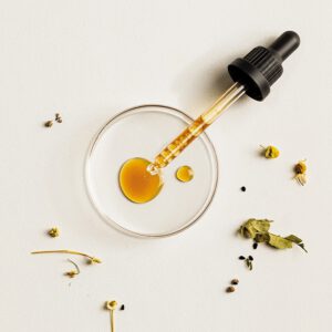 BioBloom Frauen Kräuter-Essenz "Für Sie" Detailaufnahme: Pipette tropft in Petrischale mit getrockneten Kräutern