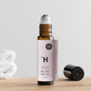 BioBloom Head On CBD Roll-On auf Holztisch mit weißem Handtuch im Hintergrund